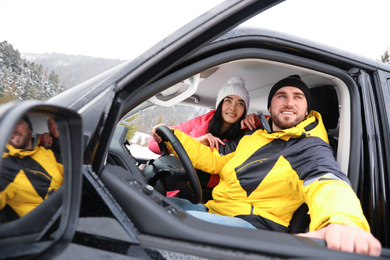 Happy couple in car outdoors. Winter vacation