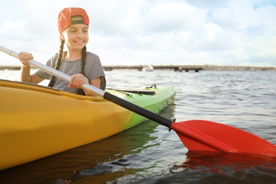 Happy little girl kayaking on river. Summer camp activity