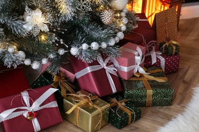 Pile of gift boxes near beautiful Christmas tree indoors