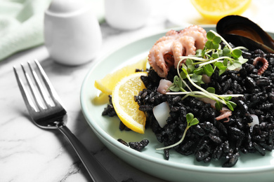 Delicious black risotto with seafood on white marble table, closeup