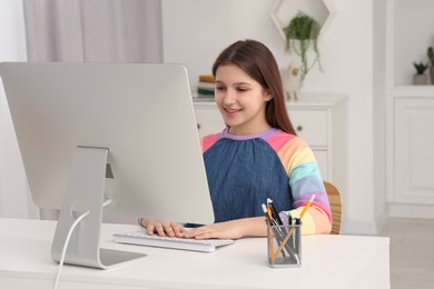 Photo of Cute girl using computer at desk in room. Home workplace
