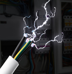 Sparking cables against blurred electric cabinet, closeup