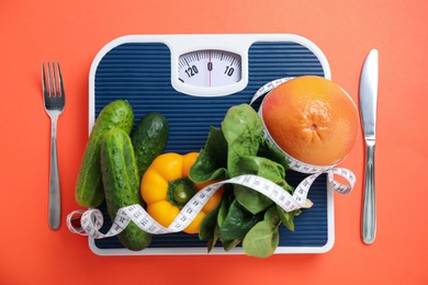 Scales, healthy food, measuring tape and cutlery on orange background, fat lay