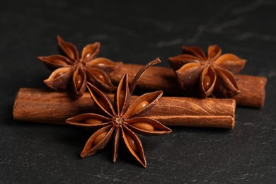 Aromatic anise stars and cinnamon sticks on black table