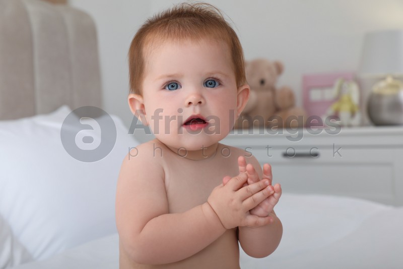 Photo of Cute little redhead baby on bed at home