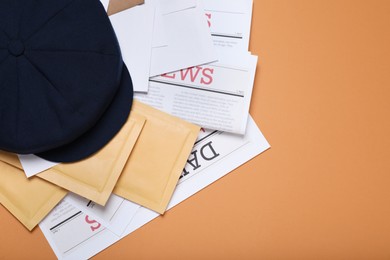 Postman hat, newspapers and mails on light brown background, flat lay. Space for text