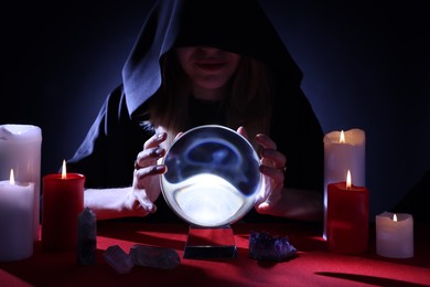 Soothsayer using crystal ball to predict future at table in darkness. Fortune telling