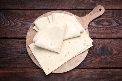 Photo of Delicious folded Armenian lavash on wooden table, top view