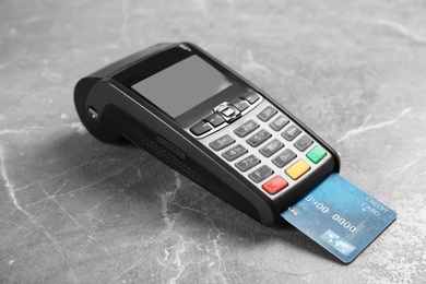 Modern payment terminal with credit card on grey background