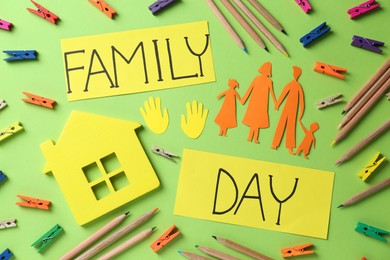 Happy Family Day. Cards with text, paper people cutout, house model and stationery on light green background, flat lay