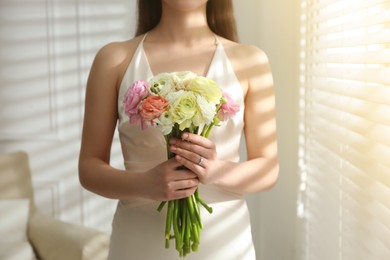 Bride with beautiful ranunculus bouquet indoors, closeup
