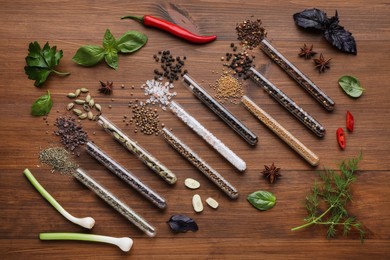 Flat lay composition with various spices, test tubes and fresh herbs on wooden background