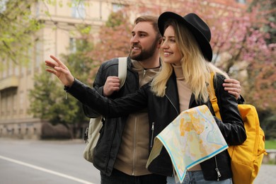 Couple of tourists with map planning trip on city street