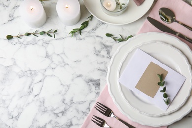 Elegant festive table setting with blank card on white marble background, flat lay. Space for text