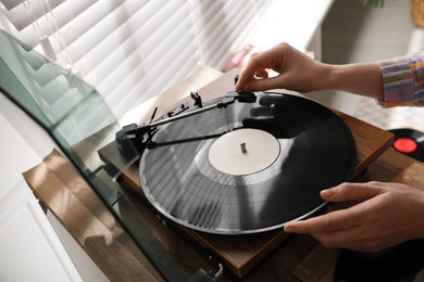 Young woman using turntable at home, closeup