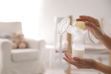 Photo of Closeup view of woman holding manual breast pump indoors, space for text. Baby health