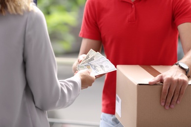 Woman paying courier for delivered parcel on doorstep