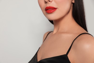 Young woman wearing beautiful red lipstick on light gray background, closeup
