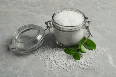 Natural sea salt in glass jar and mint on light grey marble table