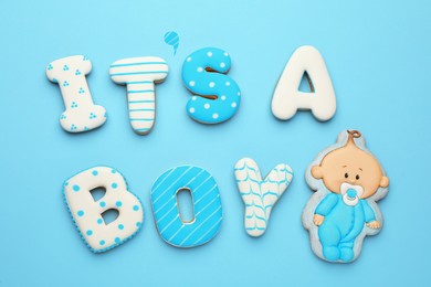 Phrase IT IS A BOY made of tasty cookies on light blue background, flat lay. Baby shower party