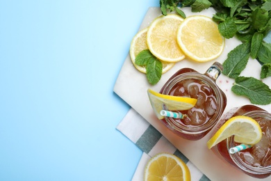 Delicious iced tea with lemon and mint on light blue background, flat lay. Space for text
