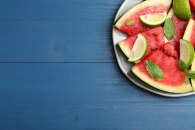 Plate with juicy watermelon and lime on blue wooden table, top view. Space for text