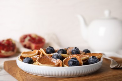 Delicious mini pancakes cereal with blueberries on wooden board