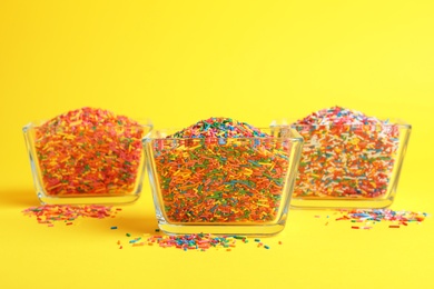 Colorful sprinkles in bowls on yellow background. Confectionery decor