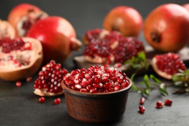 Delicious ripe pomegranate kernels in bowl on black table