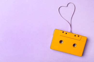Top view of music cassette and heart made with tape on violet background, space for text. Listening love song
