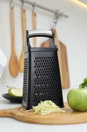 Grater and fresh ripe apple on kitchen counter
