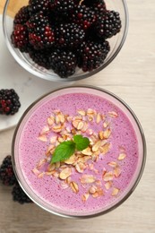 Delicious blackberry smoothie with oatmeal and berries on white wooden table, flat lay