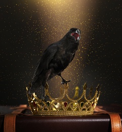 Fantasy world. Black crow lit by magic light sitting on golden crown 