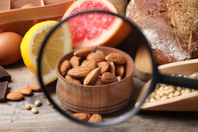 Different products with magnifier focused on almonds, closeup. Food allergy concept