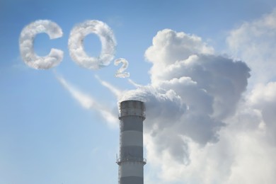  Inscription CO2 made of smoke. Polluting air from industrial chimney outdoors against blue sky 