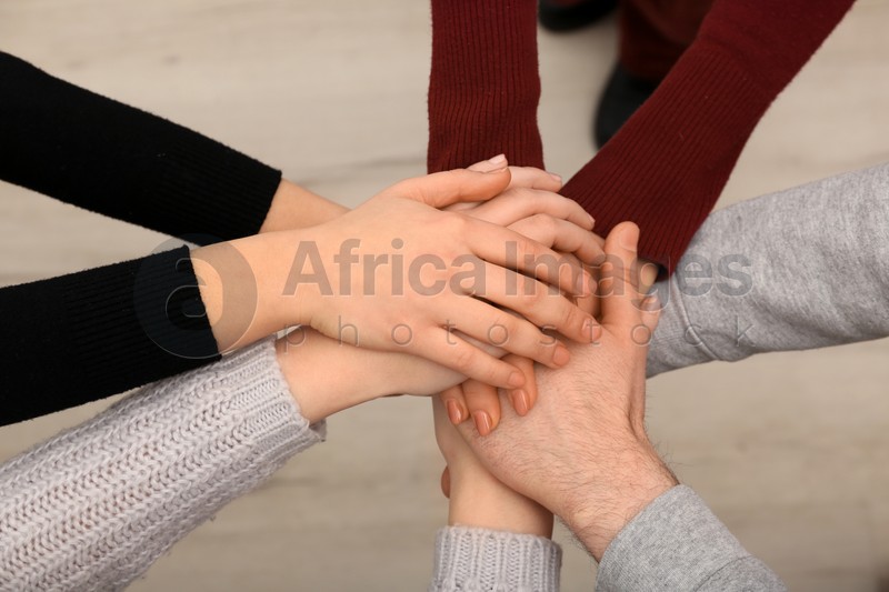 Young people putting their hands together indoors, closeup