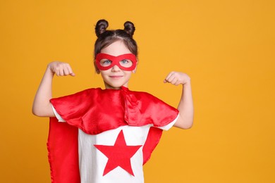 Cute little girl in superhero suit on yellow background. Space for text