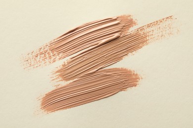 Samples of liquid skin foundations on beige background, top view