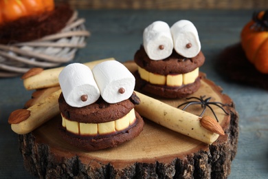 Delicious desserts decorated as monsters on stump, closeup. Halloween treat