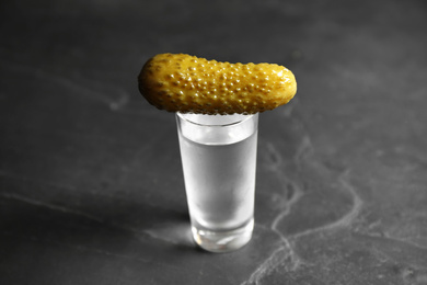 Cold Russian vodka with pickle on black table, closeup