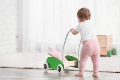 Cute baby with toy walker at home