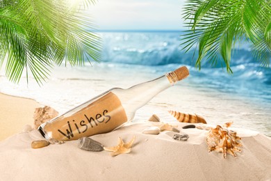 Corked glass bottle with rolled paper note and seashells on sandy beach with palms near ocean