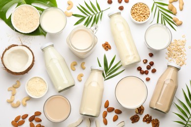 Different vegan milks and ingredients on white background, flat lay