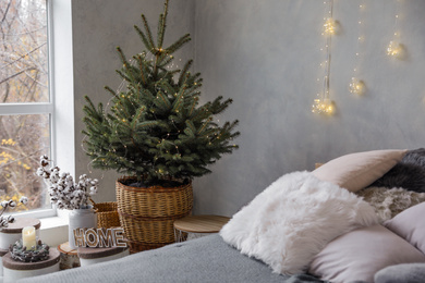 Little Christmas tree with fairy lights in bedroom interior