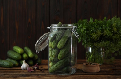 Pickling jar with fresh cucumbers on wooden table