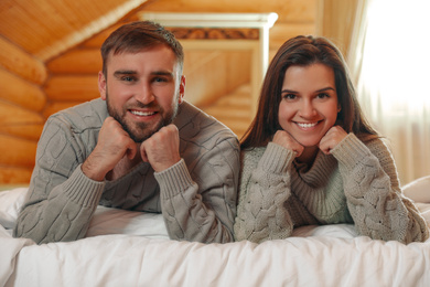Young couple wearing warm sweaters on bed at home