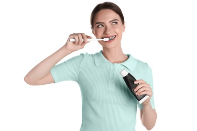 Young woman brushing teeth with charcoal toothpaste on white background