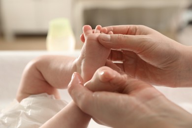 Mother massaging her cute baby with oil indoors, closeup