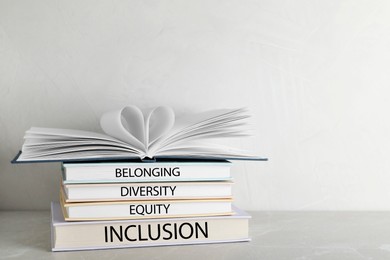Stack of hardcover books with words Belonging, Diversity, Equity, Inclusion on table against white background