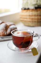 Photo of Tea bag in glass cup on white windowsill